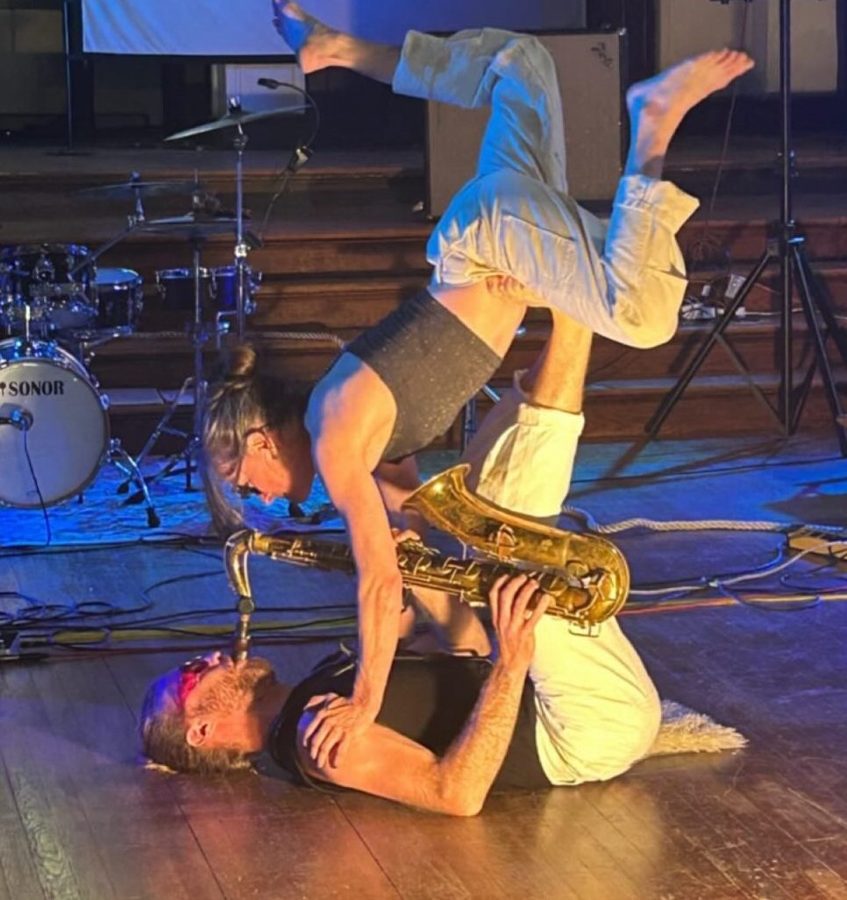 Nina Isabelle balancing on Peyton Pleninger’s feet as he plays saxophone on his back